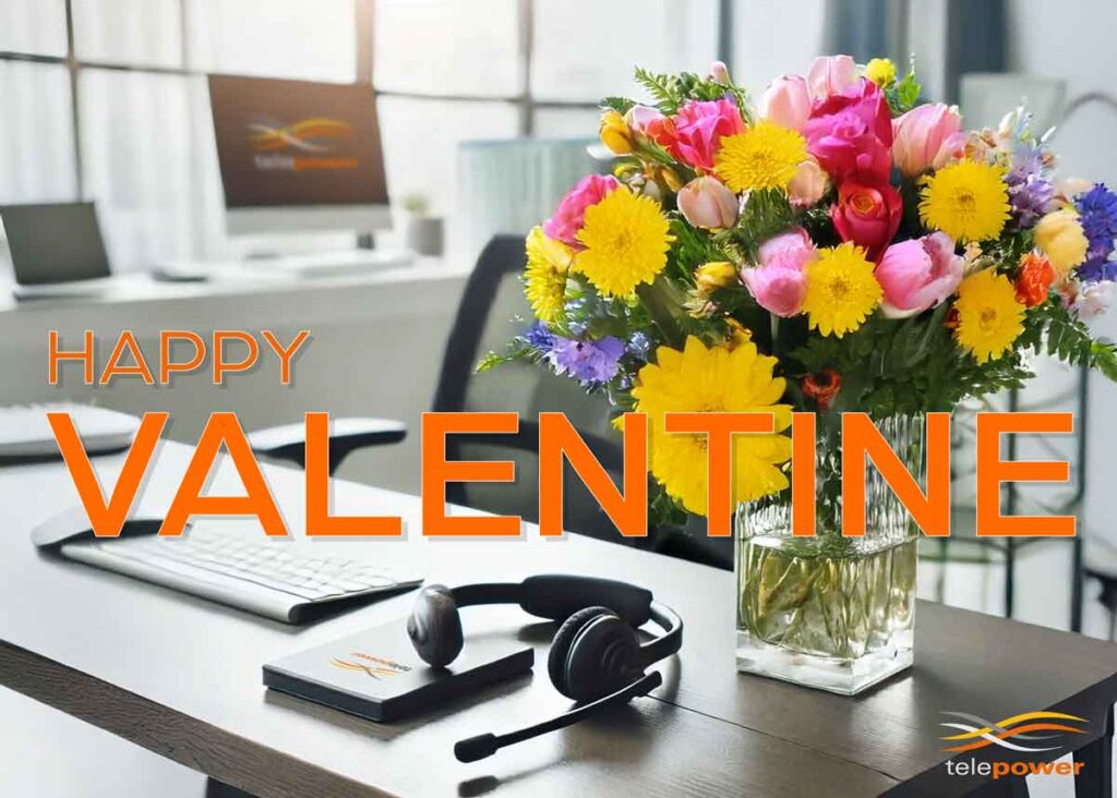 A bouquet of colourful flowers in a vase on a desk with headphones and a notepad.