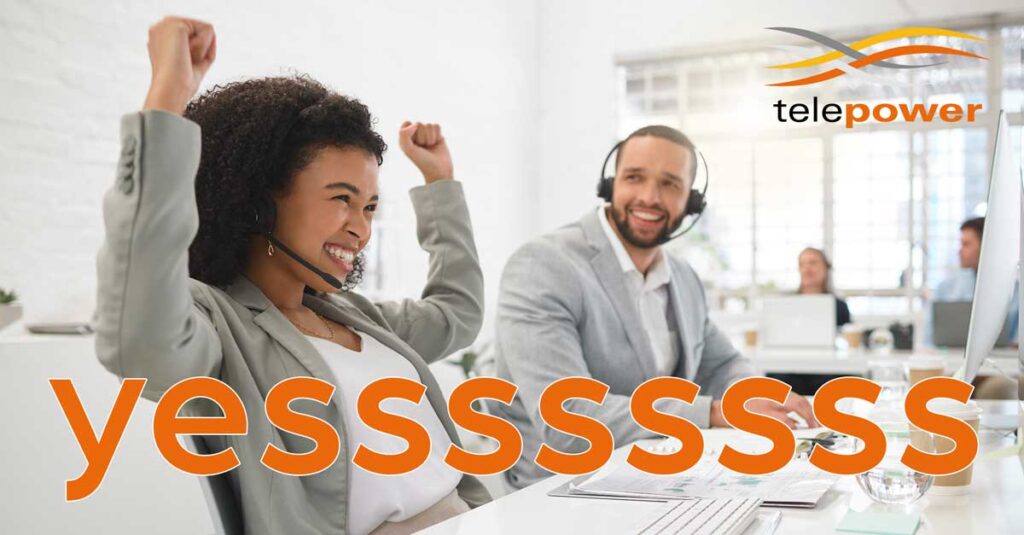 Two office workers with headsets, one smiling and raising his arms in joy.